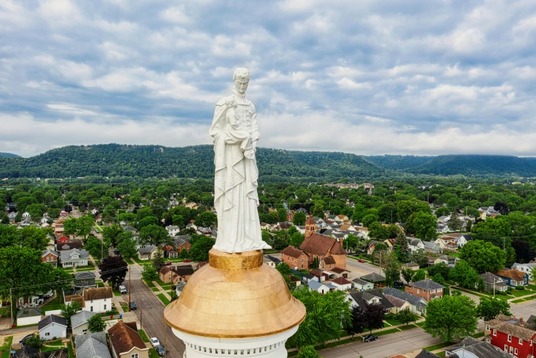 a statue of a woman on top of a building, a statue, by Mike Bierek, renaissance, drone photograph, beautiful small town, beautiful gold saint, panoramic shot