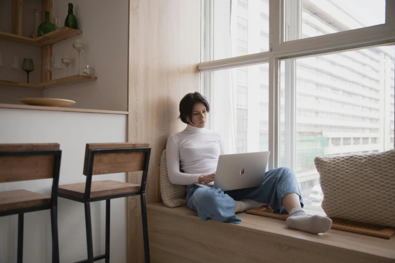 a woman sitting on a window sill using a laptop, trending on pexels, figuration libre, sitting in a lounge, “ full body, studious, rectangle