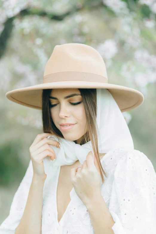 a woman wearing a hat and a scarf, inspired by Anita Malfatti, trending on pexels, renaissance, ivory and copper, light blush, middle eastern, lush surroundings