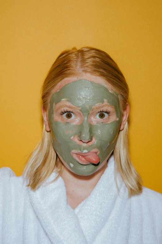 a woman with a green mask on her face, by Ellen Gallagher, trending on pexels, cute silly face, photoshoot for skincare brand, blonde swedish woman, face and body clearly visible