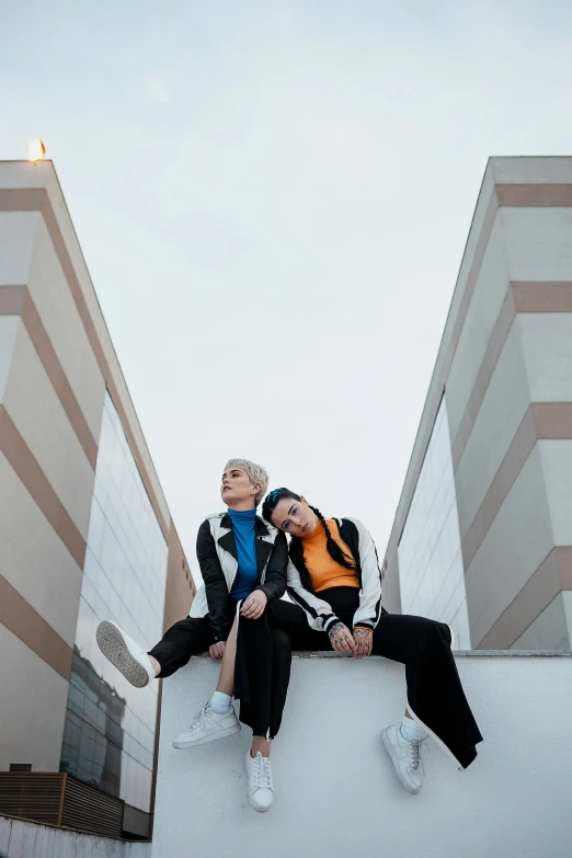 a couple of people sitting on top of a building, an album cover, inspired by Wang Duo, unsplash, realism, short platinum hair tomboy, lesbians, wearing a track suit, official store photo