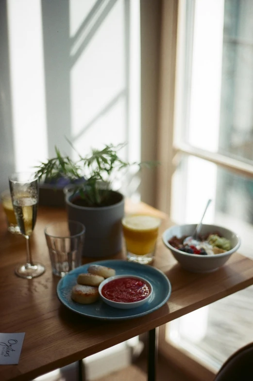 a wooden table topped with plates of food, by Constantin Hansen, unsplash, vignette of windowsill, drink, plate of borscht, lounge