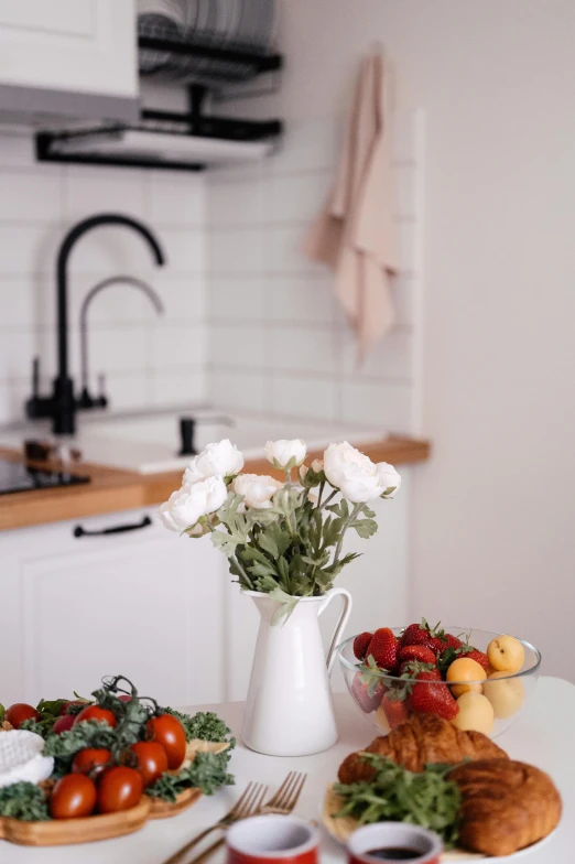 a table topped with plates of food next to a vase of flowers, unsplash, realism, strawberries, white kitchen table, background image, sink