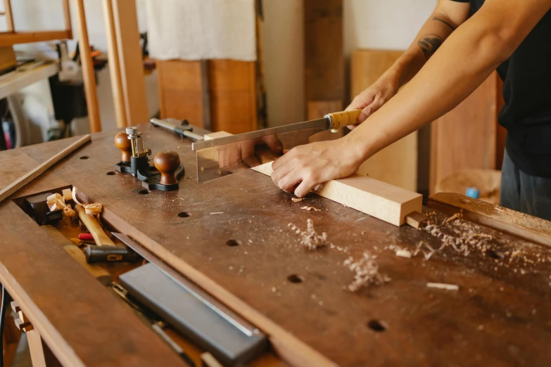 a person cutting a piece of wood on a workbench, trending on pexels, arts and crafts movement, nishimiya shouko, julia sarda, thumbnail, iconic scene