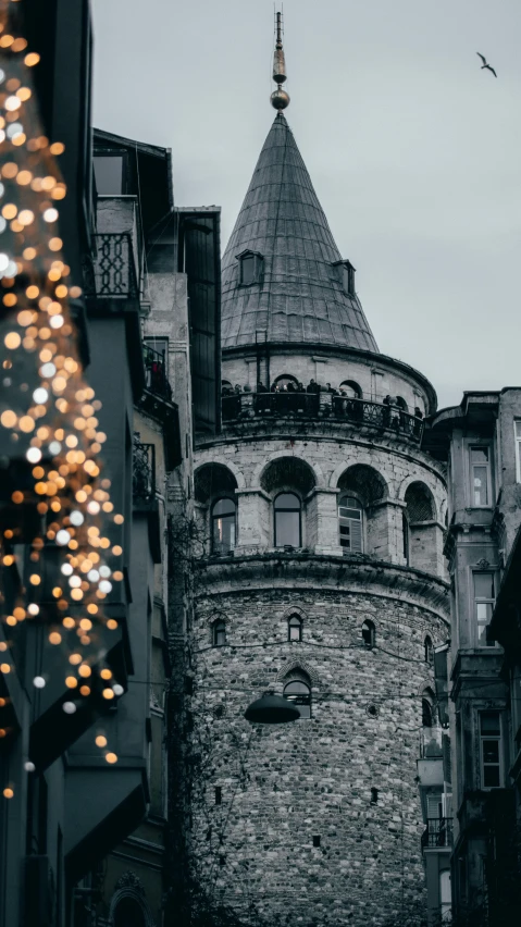 a black and white photo of a clock tower, by Matija Jama, pexels contest winner, art nouveau, christmas lights, istanbul, crenellated balconies, professionally color graded