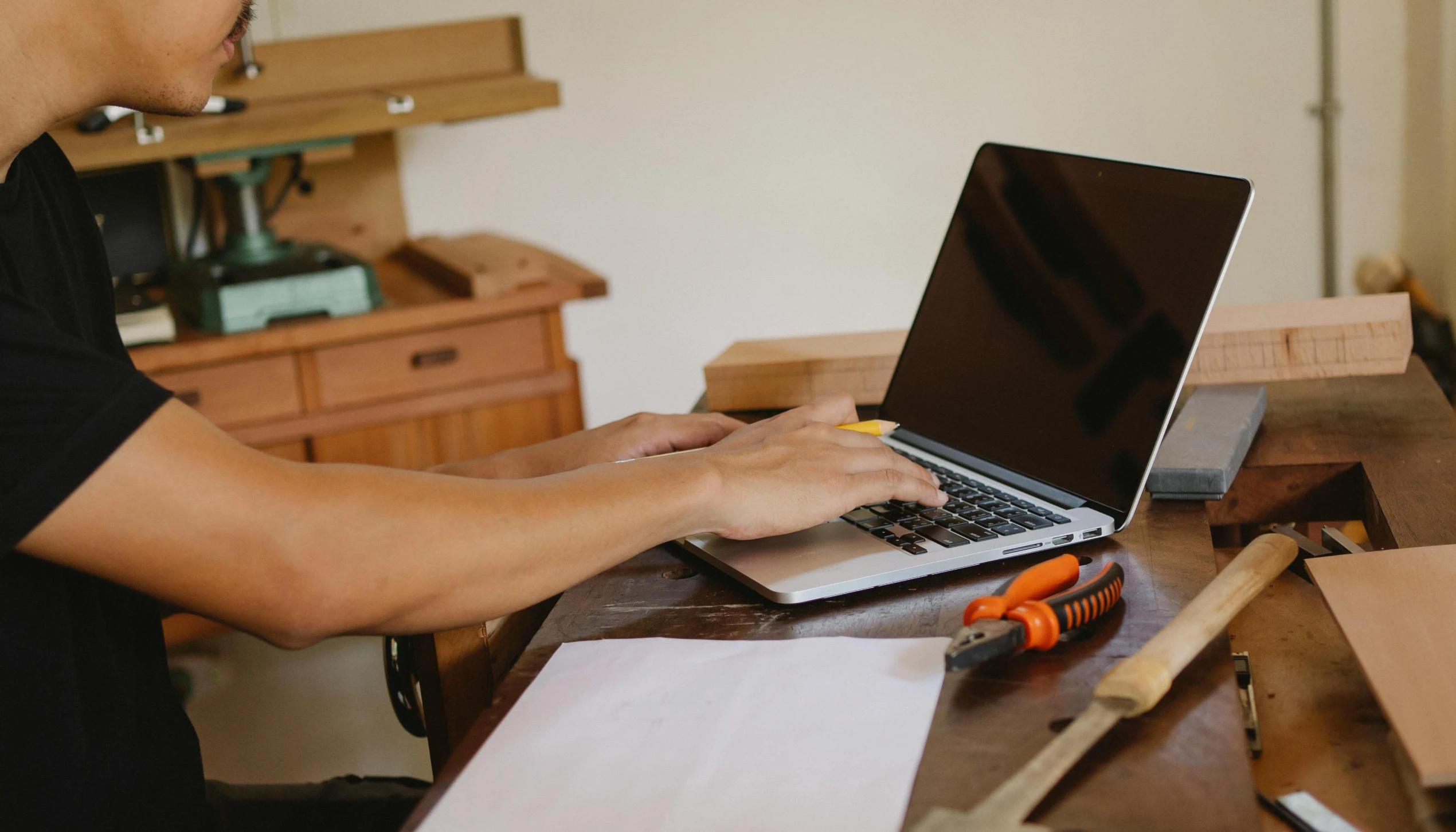 a man sitting at a table working on a laptop, by Carey Morris, trending on pexels, carpenter, background image, rectangle, cardboard