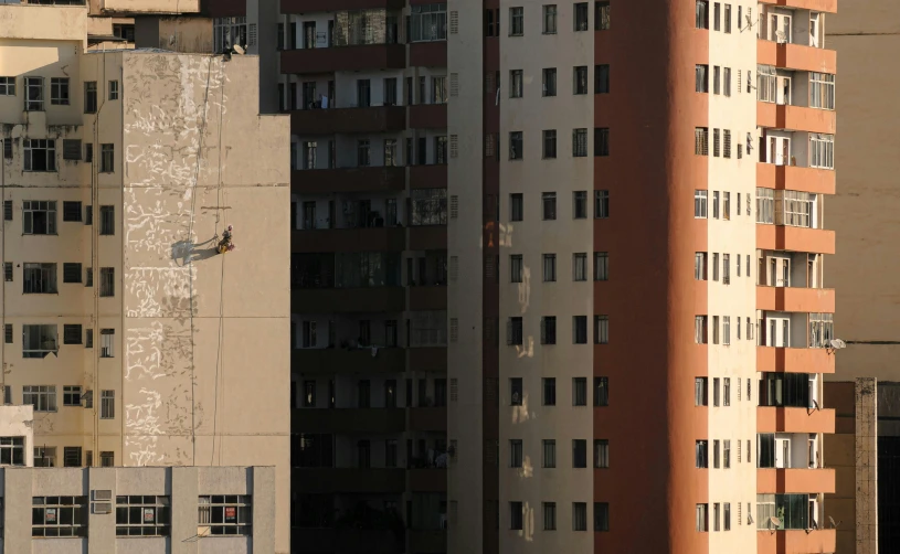 a couple of tall buildings next to each other, by Joze Ciuha, brutalism, mid air shot, person in foreground, 4 0 0 mm f 1. 8, morning detail