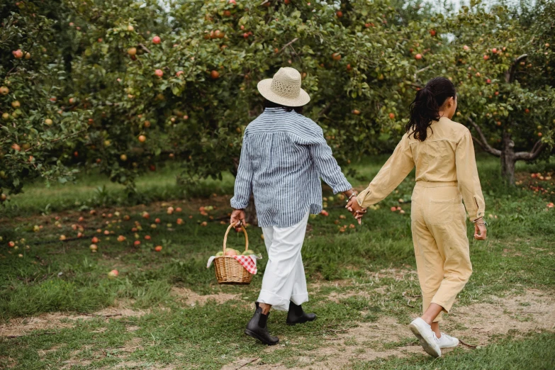 two people walking through an apple orchard holding hands, pexels contest winner, picnic, wearing farm clothes, woman holding another woman, walking through a suburb