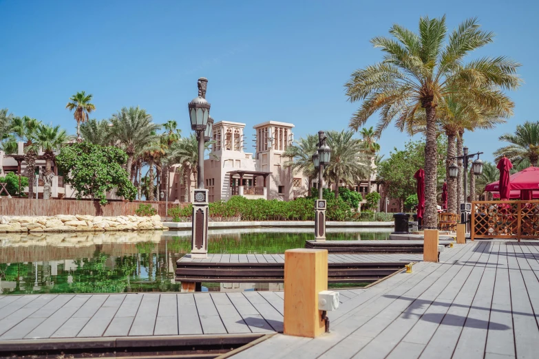 a wooden walkway next to a body of water, inspired by Ricardo Bofill, pexels contest winner, arabic architecture, village square, gta : dubai, tiled fountains