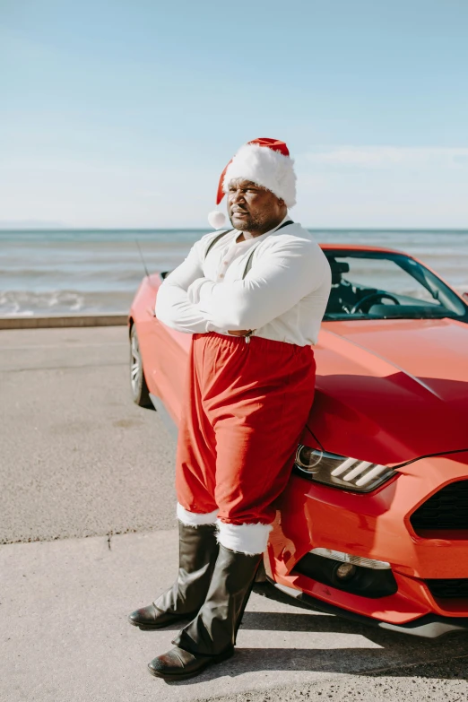 a man standing next to a red sports car, an album cover, inspired by Ernest William Christmas, pexels contest winner, wearing festive clothing, obese ), beaching, mustang