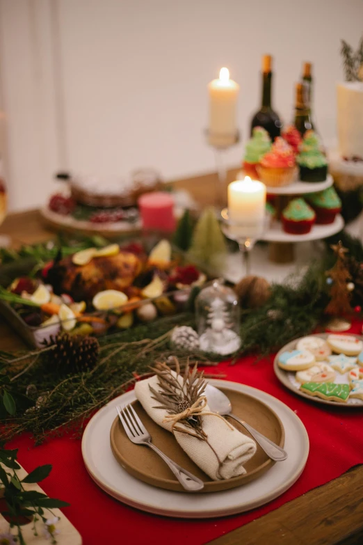 a table topped with plates of food and candles, evergreen branches, sweets, shot with premium dslr camera, medium - shot