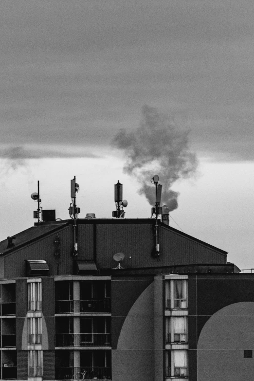 a black and white photo of a building with smoke coming out of it, a black and white photo, pexels contest winner, precisionism, transmitters on roof, :: morning, smoking vessels, my home