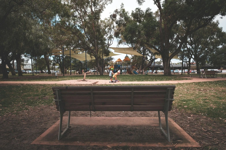 a person sitting on a bench in a park, straya, people walking in the distance, kids place, unsplash photo contest winner