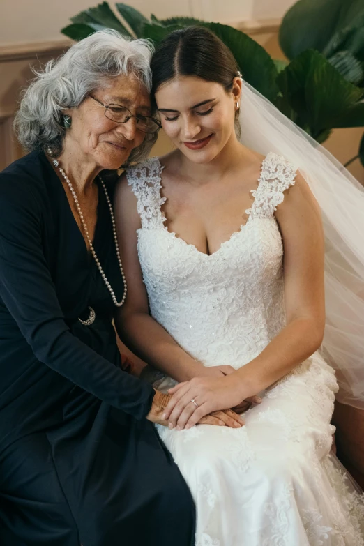 a woman sitting next to a woman in a wedding dress, a photo, by Elizabeth Durack, trending on unsplash, an elderly, holding each other hands, young women, snapchat photo