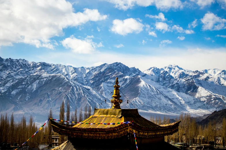 a building in the middle of a field with mountains in the background, pexels contest winner, hurufiyya, tibetan inspired architecture, snowy peaks, avatar image, background image