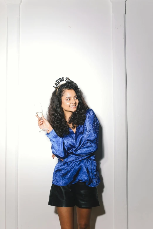 a woman standing in front of a door holding a cell phone, an album cover, pexels, renaissance, blue tiara, long wild black curly hair, new years eve, satisfied pose