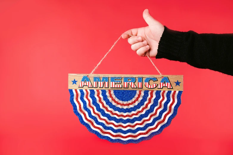 a person holding a sign that says america, by Arabella Rankin, kinetic art, decorations, trending on dezeen, fully decorated, macrame