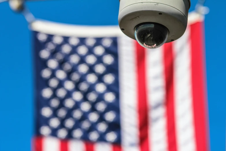 a surveillance camera with an american flag in the background, a portrait, by Dan Frazier, professional image, ultrawide lense, high - detail, american flags