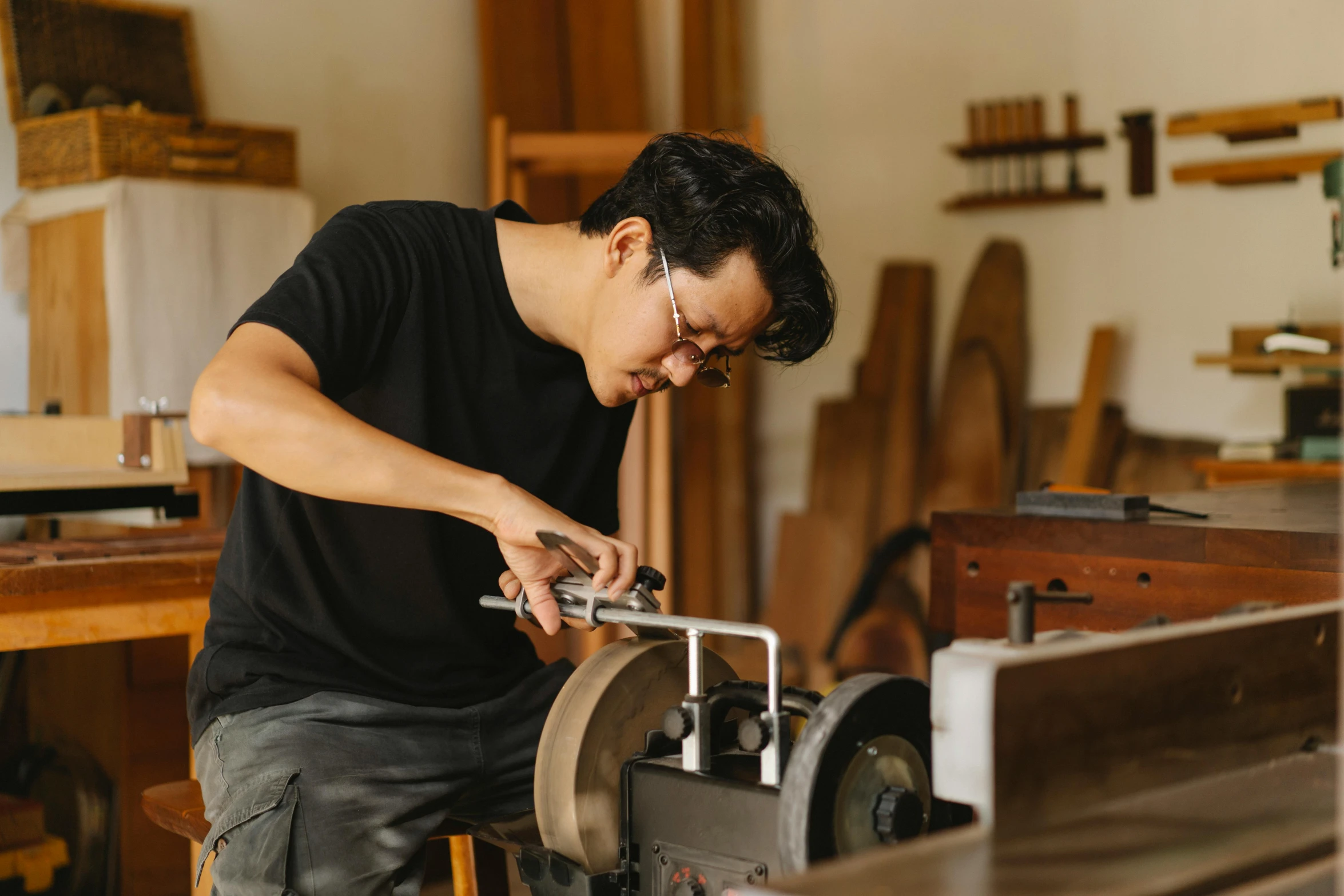 a man working on a machine in a workshop, inspired by Maruyama Ōkyo, pexels contest winner, on a wooden desk, avatar image, instrument, ross tan