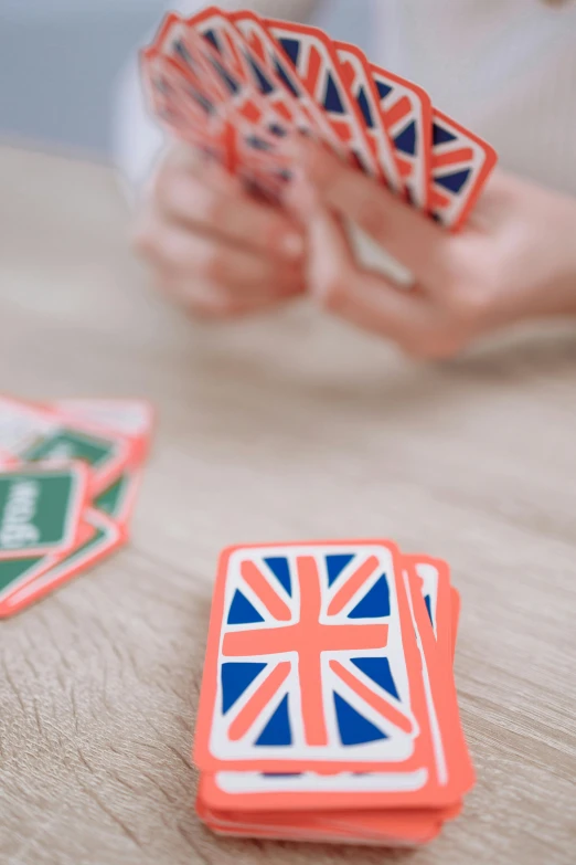 a person playing a card game on a table, union jack, language, stickers, medium close shot