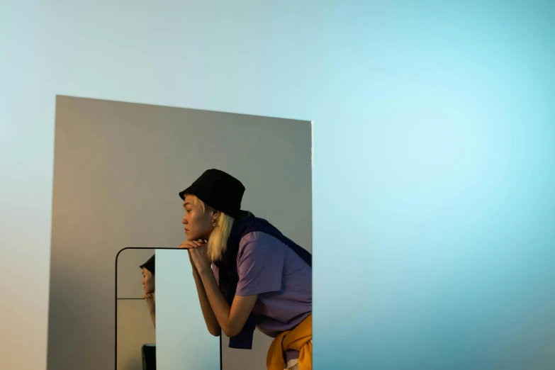 a woman looking at her reflection in a mirror, inspired by Elsa Bleda, wearing a purple cap, clemens ascher, promotional image, sideview