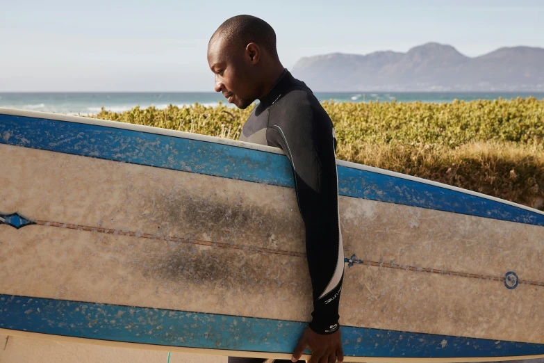 a man in a wet suit carrying a surfboard, happening, george pemba, black man, on a sunny day, kano tan'yu