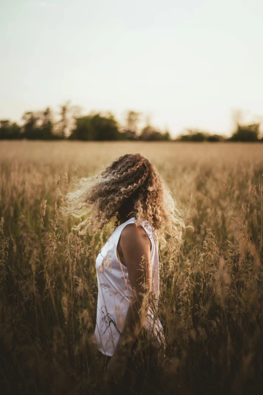 a woman standing in a field of tall grass, pexels contest winner, frizzy hair, fading off into the distance, plain background, disheveled