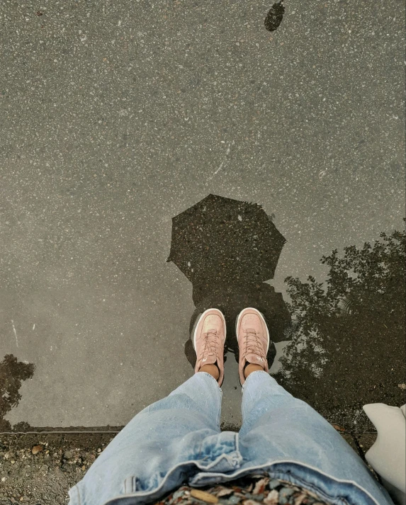 a person standing in the rain with an umbrella, snapchat photo, sitting on the ground, looking up onto the sky, reflective surface
