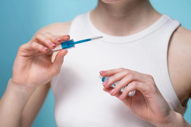 a close up of a person holding a toothbrush, wearing a blue dress, syringe, nail polish, steroid use