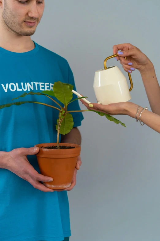 a man and a woman holding a potted plant, an album cover, by Francis Helps, pexels contest winner, watering can, printed on a cream linen t-shirt, healthcare worker, vdovenko