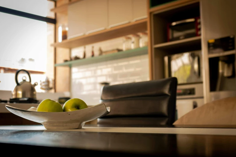 a bowl of apples on a table in a kitchen, by Niko Henrichon, unsplash, in a japanese apartment, couch desk, dwell, at the counter