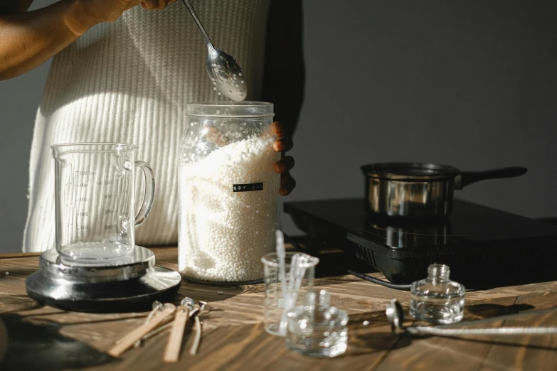 a person mixing ingredients in a jar on a table, a still life, trending on pexels, silver，ivory, rice, gif, tall