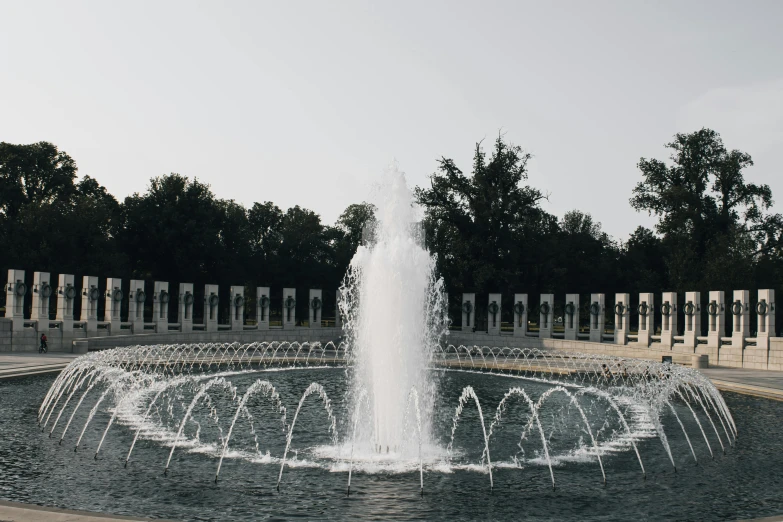 a water fountain in the middle of a park, body of water, monuments, during the day, white wall complex