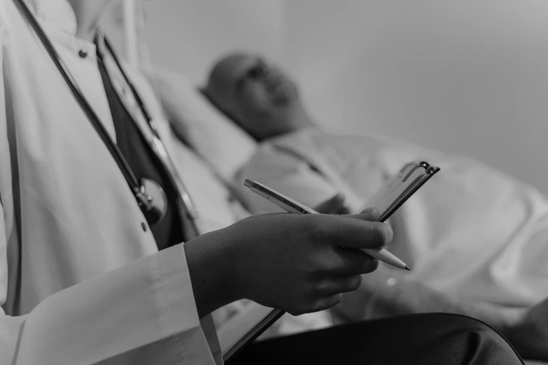 a black and white photo of a doctor writing on a clipboard, by Adam Marczyński, relaxing, digital image, thumbnail, at the hospital in patient gown