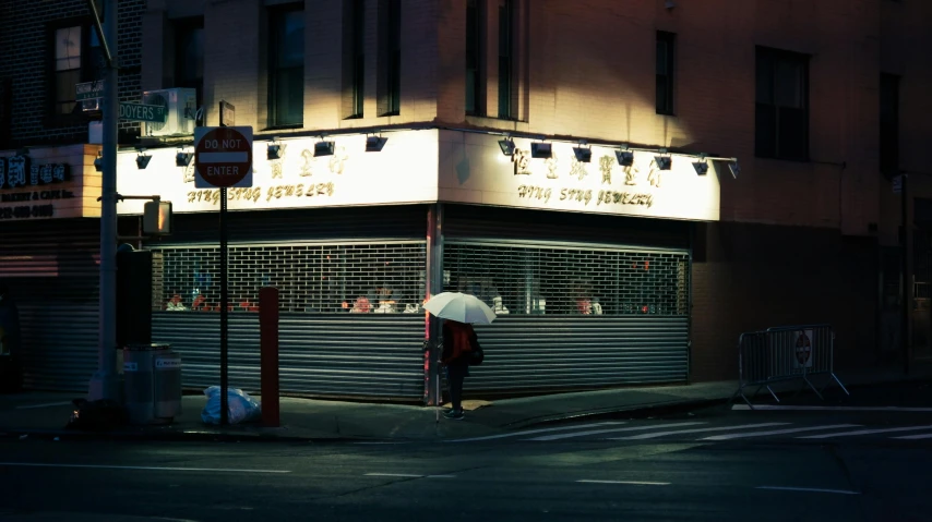 a person holding an umbrella on a city street, a photo, by Alison Geissler, shin hanga, warm street lights store front, david shing, shrines, melbourne