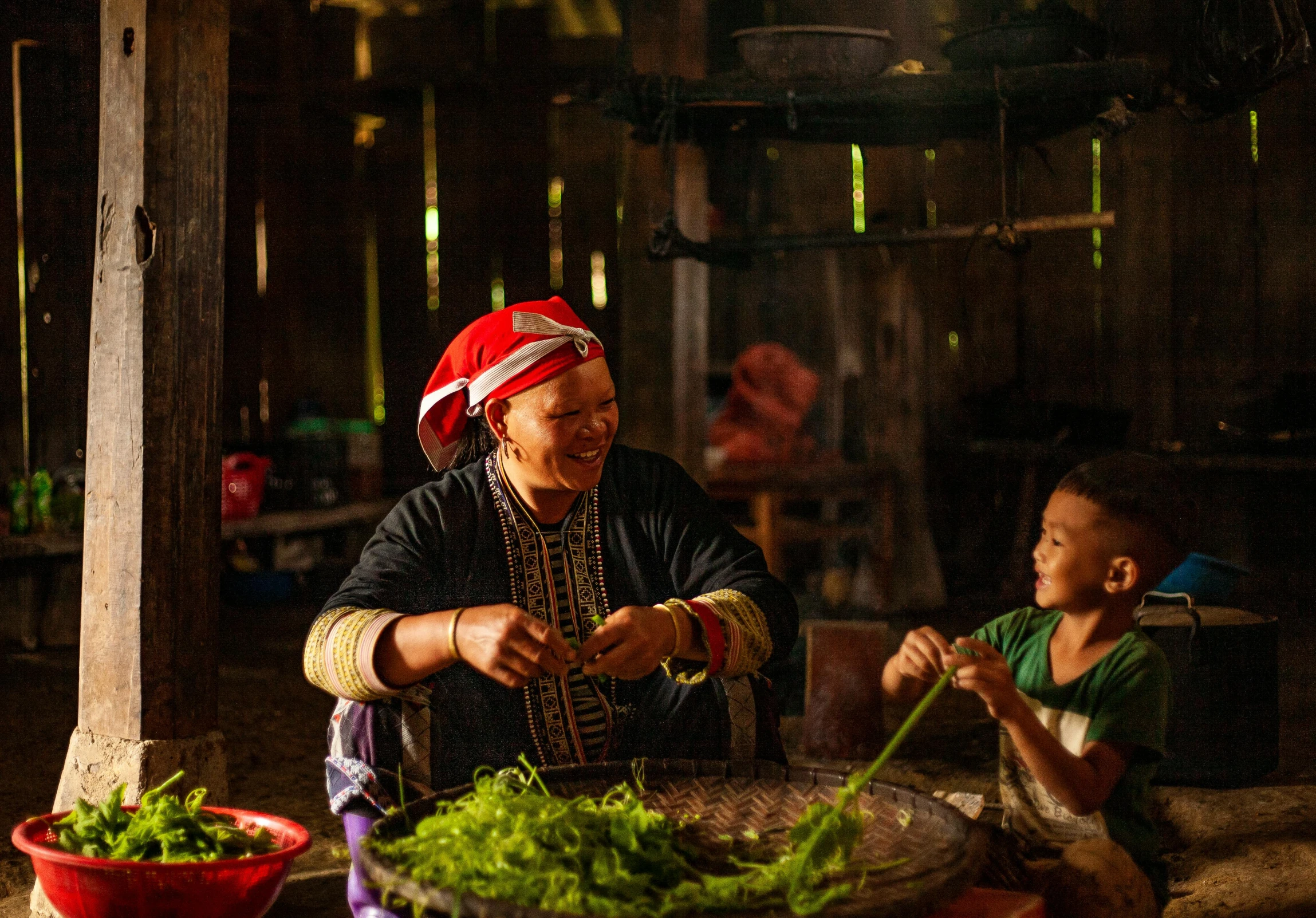 a woman sitting in front of a table filled with food, by Dan Content, pexels contest winner, tai traditional bronze headdress, with a kid, ja mong, thumbnail