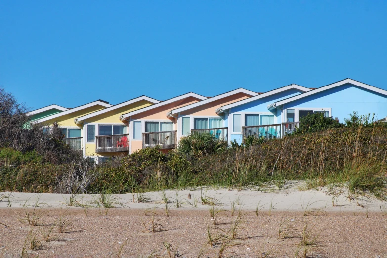 a row of houses sitting on top of a sandy beach, colorful building, exterior view, cottages, profile image