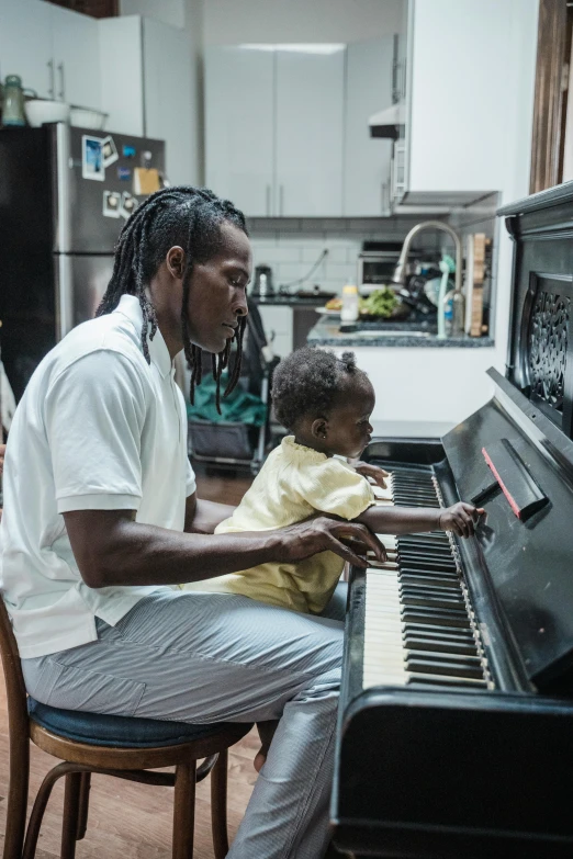 a man playing a piano with a child, black arts movement, jamaican vibe, offset and takeoff, daddy/fatherly, thumbnail