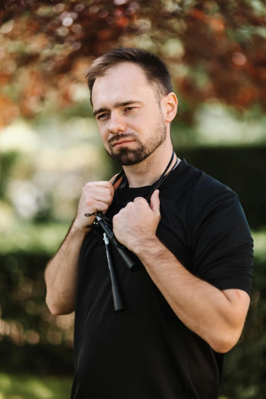 a man in a black shirt standing under a tree, with lightsaber sword, jovana rikalo, holding arms on holsters, profile image