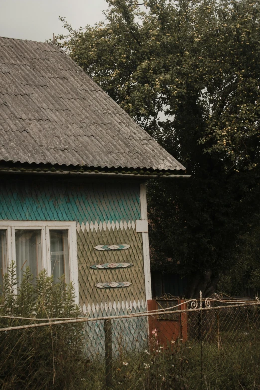 a blue and white house behind a chain link fence, an album cover, inspired by Isaac Levitan, unsplash, thatched roofs, faded colours, russian village, low quality photo