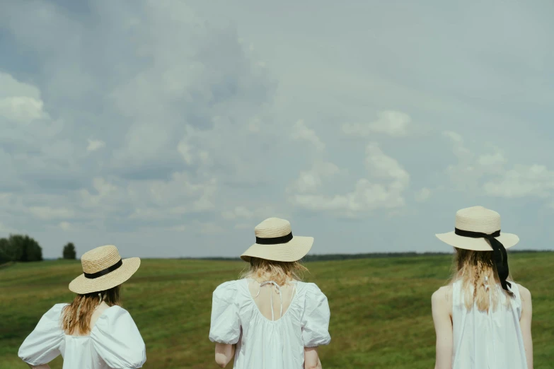 three women in white dresses and hats standing in a field, inspired by Wilhelm Hammershøi, unsplash, girl clouds, exterior shot, prairie, a group of people