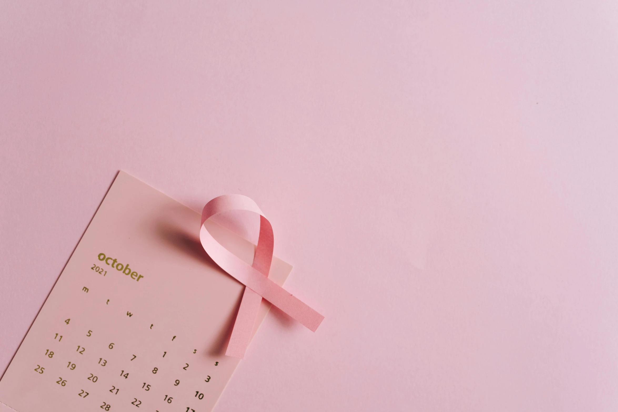 a calendar with a pink ribbon on top of it, a photo, by Emma Andijewska, trending on pexels, tumors, pink background, background image, instagram post