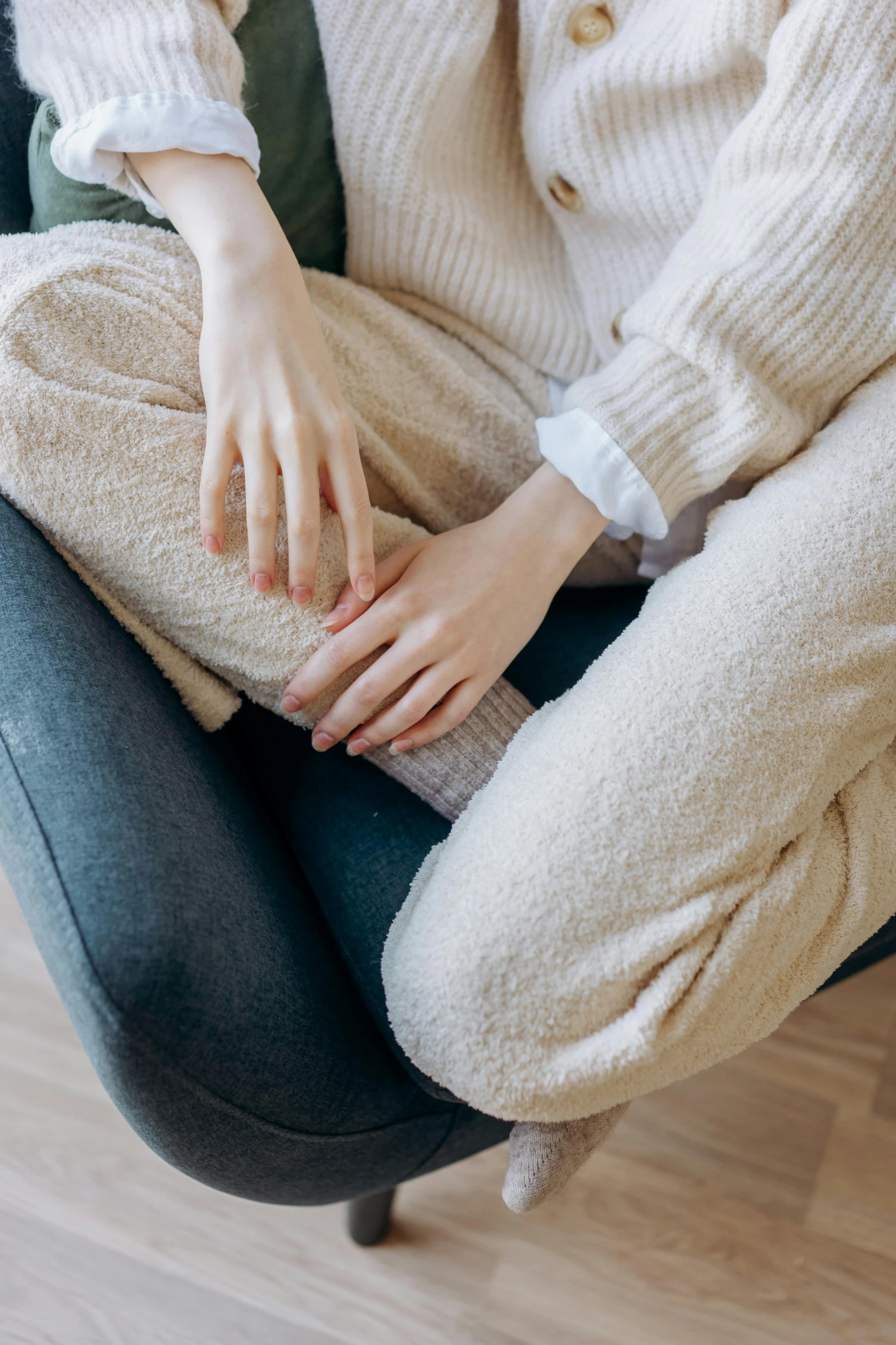 a woman sitting on top of a blue chair, inspired by Elsa Bleda, trending on pexels, renaissance, wearing a white sweater, swollen veins, beige, manuka