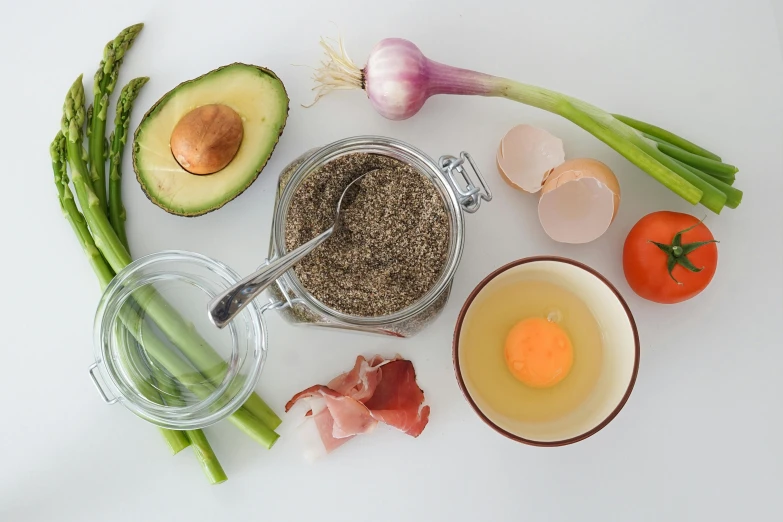 a table topped with eggs, asparagus, and other ingredients, a still life, inspired by Géza Dósa, pexels, on a gray background, background image, avocado, ground - level medium shot