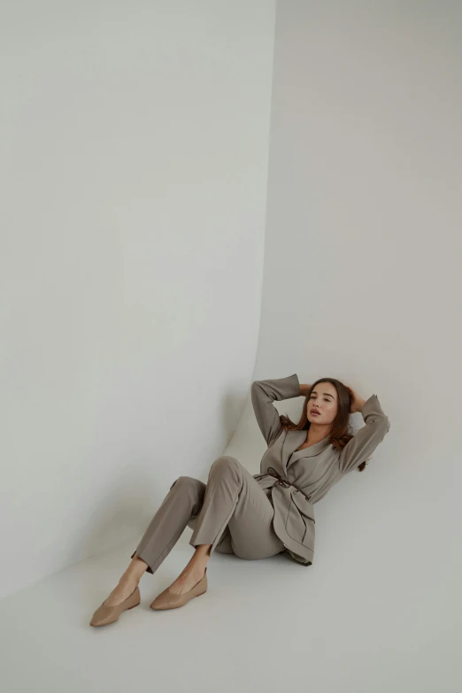 a woman sitting on the floor in a white room, a picture, trending on pexels, renaissance, tan suit, kim hyun joo, taupe, outfit photo