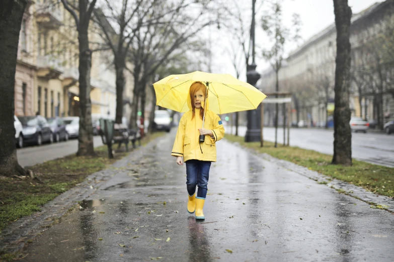 a woman walking down a street holding an umbrella, pexels, yellow raincoat, little girl, aleksandra waliszewska, a blond