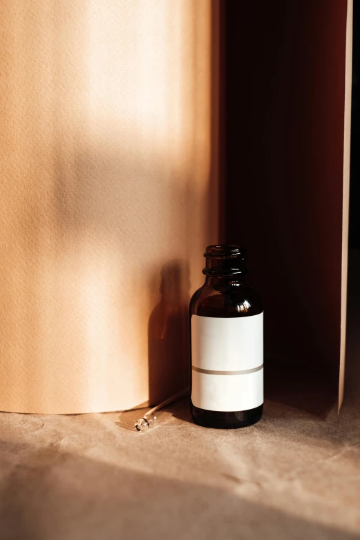 a bottle of essential oil sitting next to a book, by Jessie Algie, purism, ignant, abstract detail, smooth panelling, cardboard