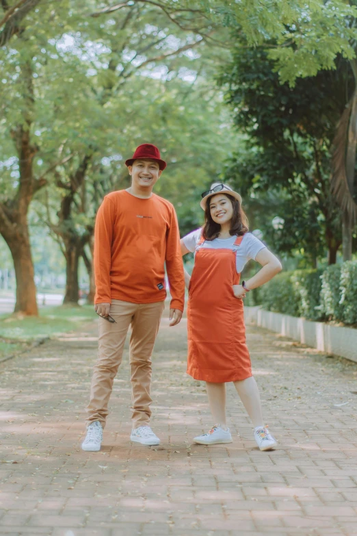 a man and a woman standing next to each other, instagram, orange color theme, kuntilanak, in a park, high-quality photo