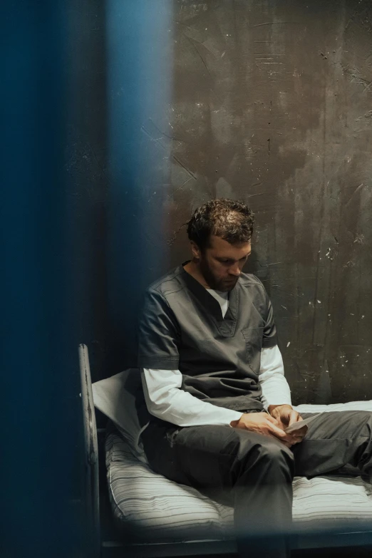 a man sitting on a bed in a jail cell, unsplash, serial art, henry cavill, devastated, charlie day, sitting in a waiting room