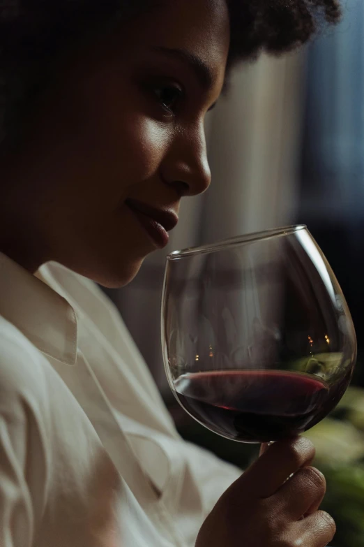 a woman holding a glass of red wine, a portrait, pexels contest winner, dark skinned, close up half body shot, profile image, smug look